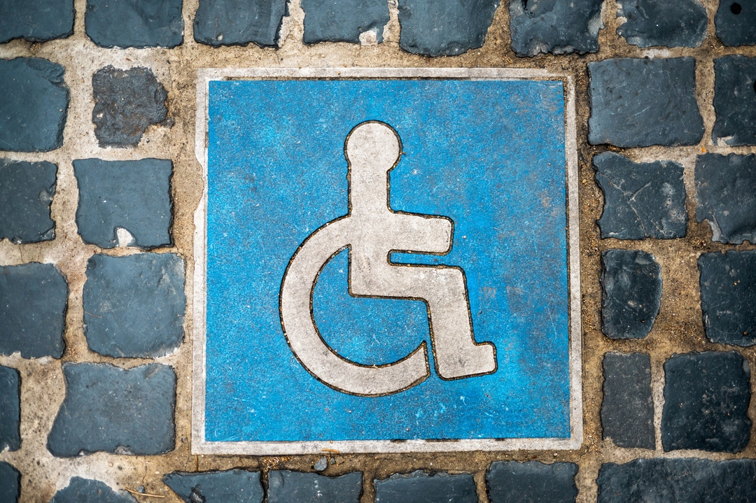 simbolo della disabilità disegnato su un muro di pietra
